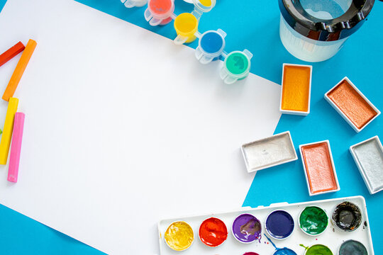 A bright and colorful photo with art supplies, including paints, pencils, crayons, and a palette on a vivid background.