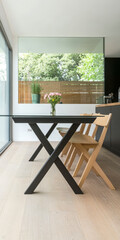 Modern dining area with glass walls and wooden accents featuring a floral centerpiece