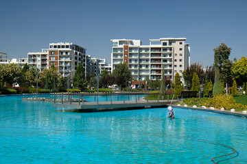 Fototapeta premium artificial pond with blue water in the park and buildings in the background, Tashkent