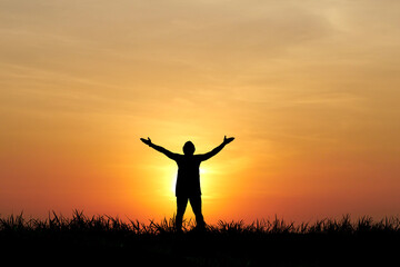 Embrace the Dawn: Silhouette of a person standing with arms outstretched, basking in the warm glow of the sunrise. Capturing the spirit of freedom and spiritual journey 