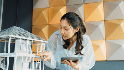 Beautiful project manager using tablet check house model. Portrait of architect engineer inspect building construction by using data analysis from tablet. Business construction concept. Manipulator.
