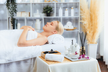Caucasian woman customer enjoying relaxing anti-stress spa massage and pampering with beauty skin recreation leisure in day light ambient salon spa at luxury resort or hotel. Quiescent