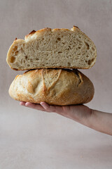 Hand Holding Rustic Artisan Sourdough Bread with Open Crumb – Crusty Homemade Loaf in Natural Light for Bakeries, Food Bloggers, and Culinary Photography – Sliced in Half