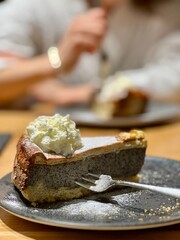 Cheesecake with a rich, creamy filling and a golden-brown crust, topped with a generous swirl of whipped cream. 