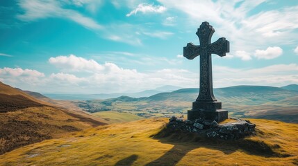 A towering stone cross stands proudly atop a hill, overlooking a vast scenic landscape beneath a clear blue sky.