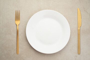 White plate with gold cutlery on the table