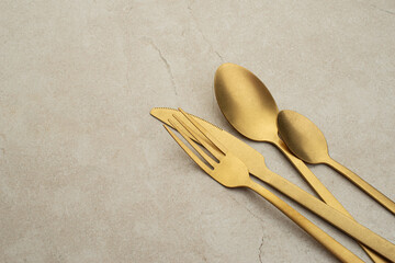 Set of golden metal cutlery on stone table