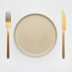 White plate with gold cutlery on the table