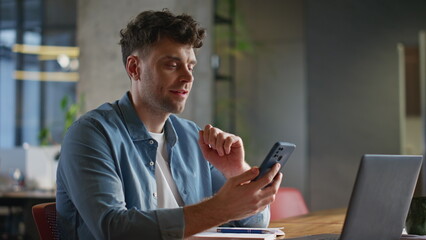 Relaxed man scrolling smartphone feed enjoying break at private cabinet closeup
