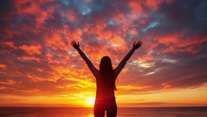 Fototapeta premium Sunset Embrace: A silhouette of a woman with arms raised towards a vibrant sunset sky, exuding freedom and a deep connection with nature, portraying a sense of peace and liberation.