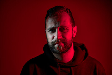 Portrait of a Bearded Man Lit in Dramatic Red and Shadowed Lighting..