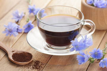 Chicory healthy drink in a glass cup with flowers on rustic wooden background, closeup, natural medicine and naturopathy concept