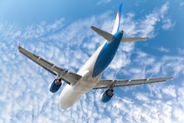 Airplane flying in blue sky with clouds, travel background