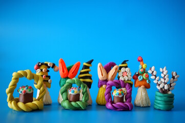 Figures of colorful gnomes and Easter made of plasticine. Blue background.