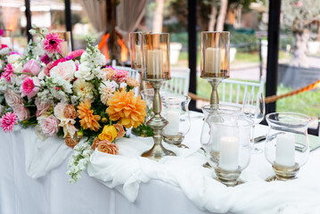 Elegant floral arrangement and candlelit setup for a romantic outdoor celebration at twilight in a garden venue