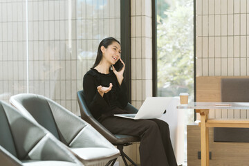 Busy Businesswoman: A focused businesswoman engages in a phone conversation while multitasking with...