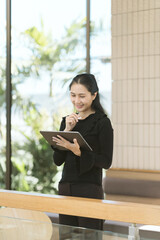 Asian Businesswoman with Tablet: Capturing the focused Asian businesswoman, deep in thought, as she...