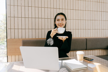 Coffee Break Moment: A modern businesswoman, content in her work environment, pauses to enjoy a...