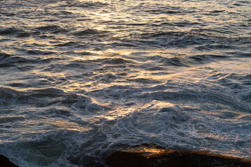 Golden sunset glimmering over wavy seascape, foaming waters near bari sardo in ogliastra, sardinian coastline, italy