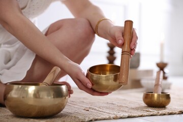 Woman with singing bowls on floor indoors, closeup