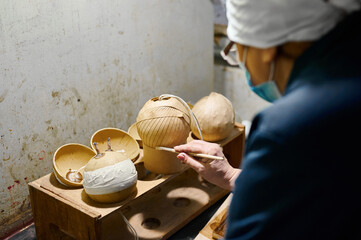 Craftsman details intricate wooden fireworks designs at a factory high-rise during a bustling...