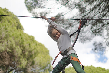 Girl hanging from a zip line, enjoying a thrilling adventure in a forest setting