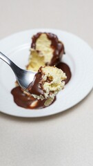 Indulgent Chocolate Fudge Sauce Drizzled Over Creamy Cheesecake Slice on White Plate