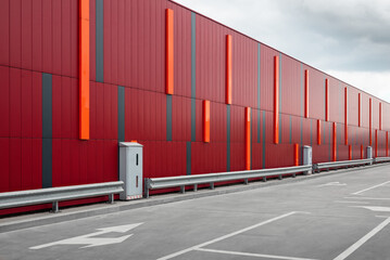 Empty parking lot near red building wall. Concrete parking lot with road markings and directional...