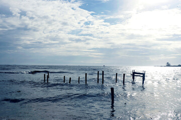 Summer afternoon on arabian sea, blue sky, clouds, and old pier pilings close to shoreline