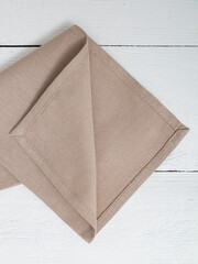 Beige napkin on a wooden white background. Closeup.