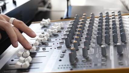 Young man in sound recording studio. Close up hands using mixing console. Professional sound...