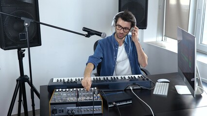 Young man in sound recording studio. Guy in slow motion adjusting music mixing console and...