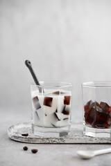 Two cups of Japanese coffee jelly with coconut milk and coffee beans in the background. Dessert made from Black coffee jelly cubes. Vegan food concept. Healthy dessert