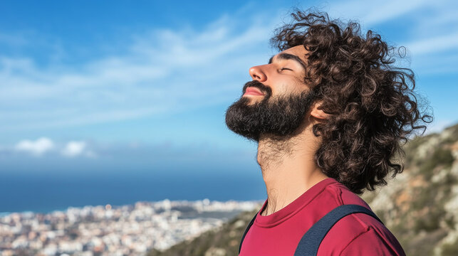 Hombre con barba y pelo rizado tomando el aire en ujn balc&oacute;n al sol
