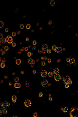 Floating iridescent bubbles with colorful glowing bokeh at night
