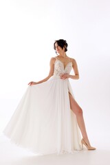 Elegant woman in white gown showcasing beauty and grace during a photoshoot in a well-lit studio environment