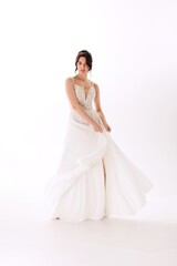 Elegant bride in a flowing white wedding gown showcasing grace and beauty during a photoshoot in a bright studio setting