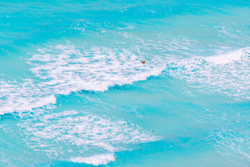 Bright orange buoys floating on turquoise Caribbean Sea with white waves and foam under strong wind in tropical watersю Mexico. Cancun.