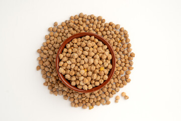 Chickpeas in a bowl on a white background with many scattered around, isolated, top view, raw uncooked legumes, healthy organic food, high-protein vegetarian ingredient, nutritious dried peas