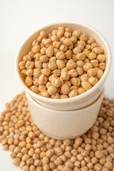 Chickpeas in a white bowl on a white background with many scattered around, isolated, raw uncooked legumes, healthy organic food, high-protein vegetarian ingredient, nutritious dried peas, agriculture