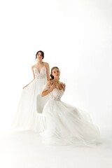 Naklejka premium Elegant bridal models showcase stunning wedding dresses in a minimalist studio setting
