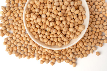 Chickpeas in a white bowl on a white background with many scattered around, isolated, raw uncooked legumes, healthy organic food, high-protein vegetarian ingredient, nutritious dried peas, agriculture