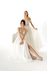 Fototapeta premium Elegant bridal gowns showcased by models in a bright studio setting during a fashion presentation