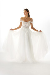 Fototapeta premium Elegant bridal gown showcased by a model in a bright studio setting emphasizing romantic design and delicate details