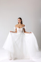 Fototapeta premium Elegant woman wearing a beautiful white gown poses gracefully in a studio setting