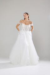 Fototapeta premium Elegant bridal gown displayed by model in studio setting during fashion showcase