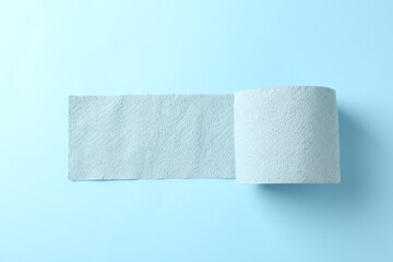 Color toilet paper roll on light blue background, top view