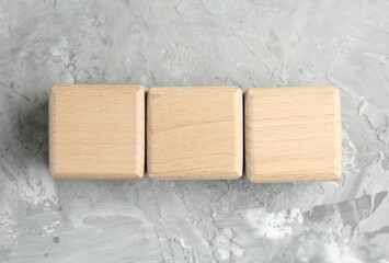 Blank wooden cubes on grey textured table, top view