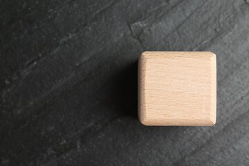 One wooden cube on dark textured table, top view. Space for text