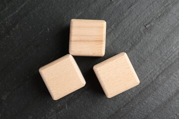 Blank wooden cubes on dark textured table, flat lay